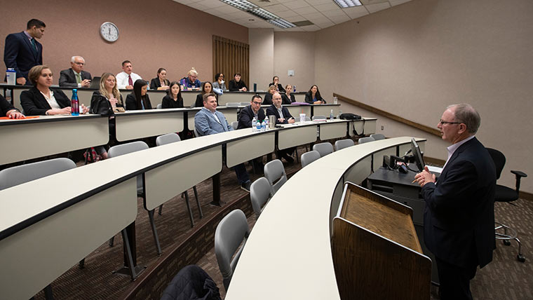 Dr. Michael Merrigan speaking to health administration students in lecture room.