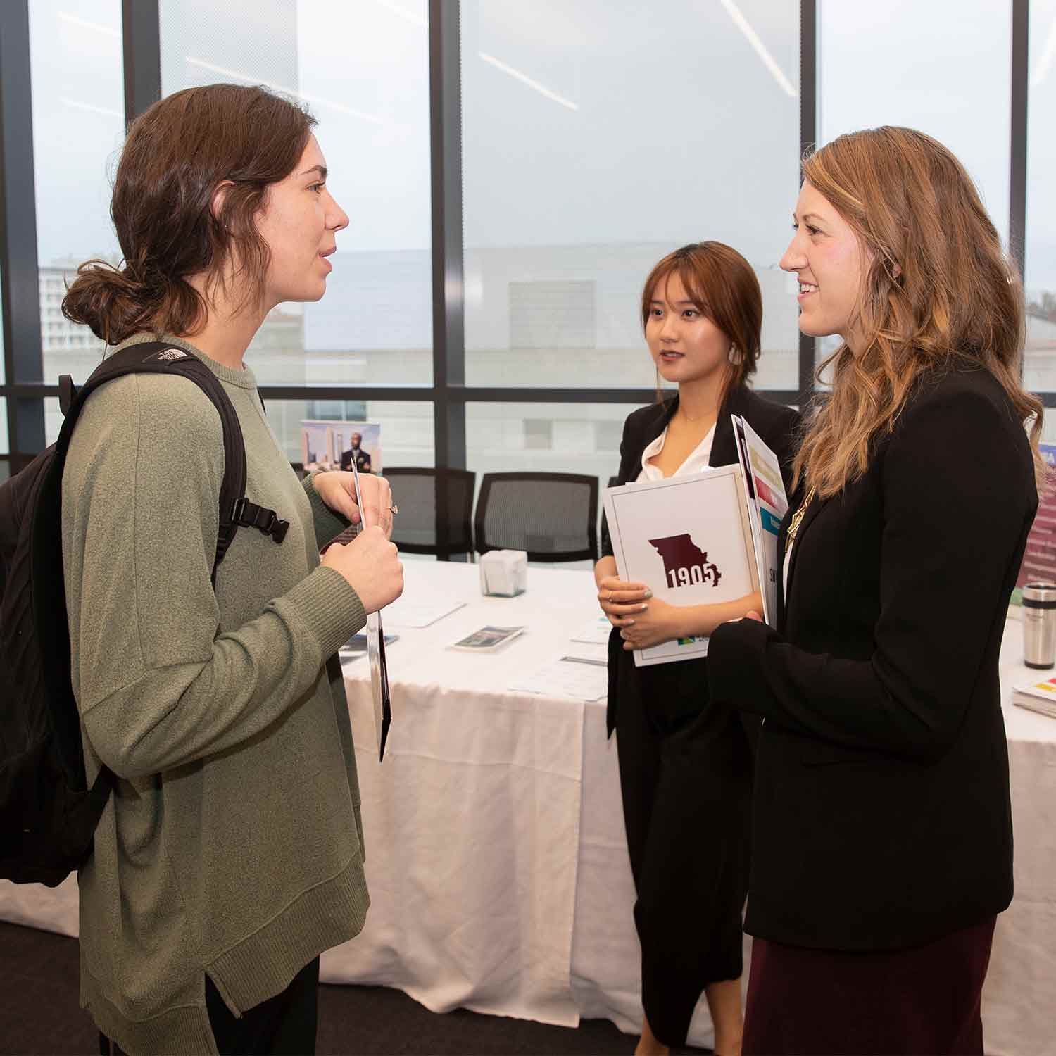 Admissions reps talking to a student at a College of Business Open House event.